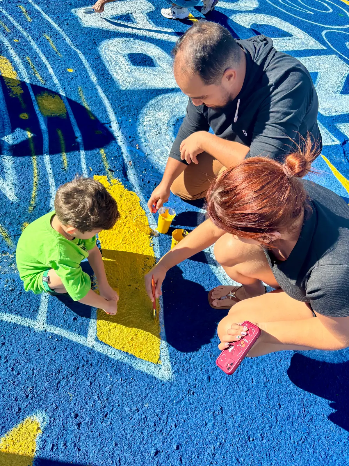 Adultos e criança participando da pintura