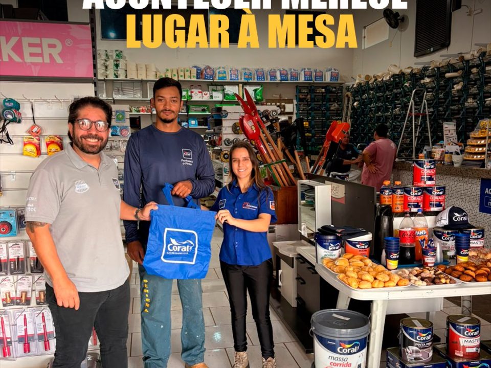 Capa do registro do Dia do Pintor na Construind, em Minas Gerais: participantes ao lado da mesa de café e de materiais Coral. Texto: Quem faz a obra acontecer merece lugar à mesa.